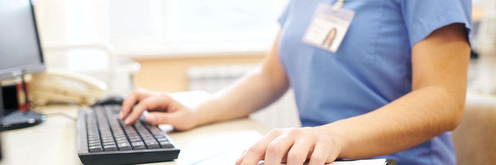 Healthcare professional entering patient data at a computer